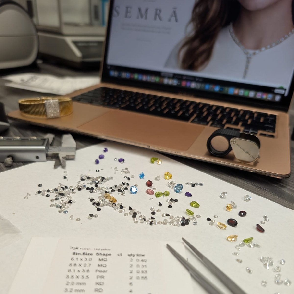 SEMRĀ workbench with loose diamonds and gemstones, loupe, tweezers and the SEMRĀ website on screen